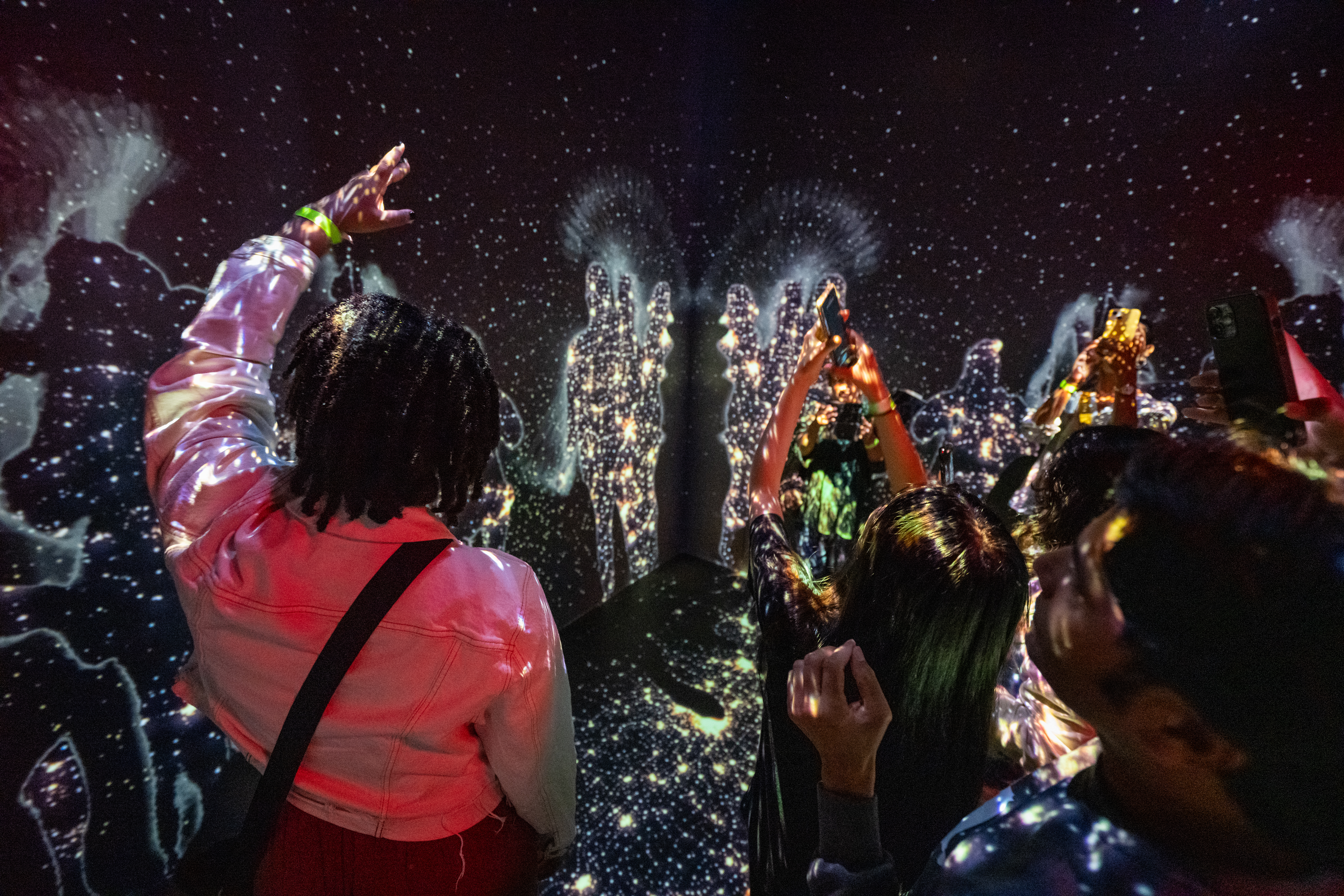 Guests at NASA HQ with their arms raised experiencing Space for Earth.s immersive display.