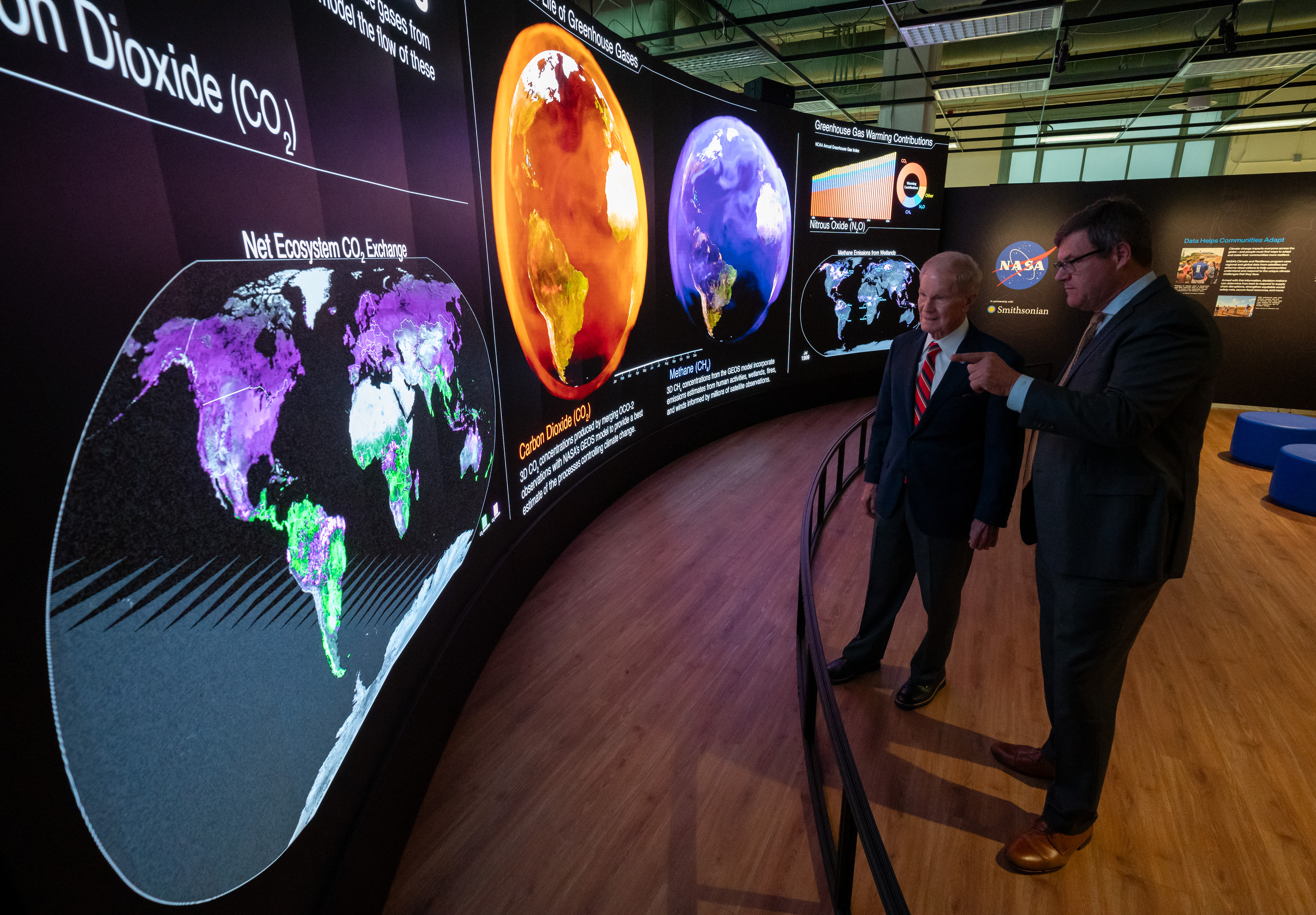 Two visitors viewing the Hyperwall and discussing the information they are reading.