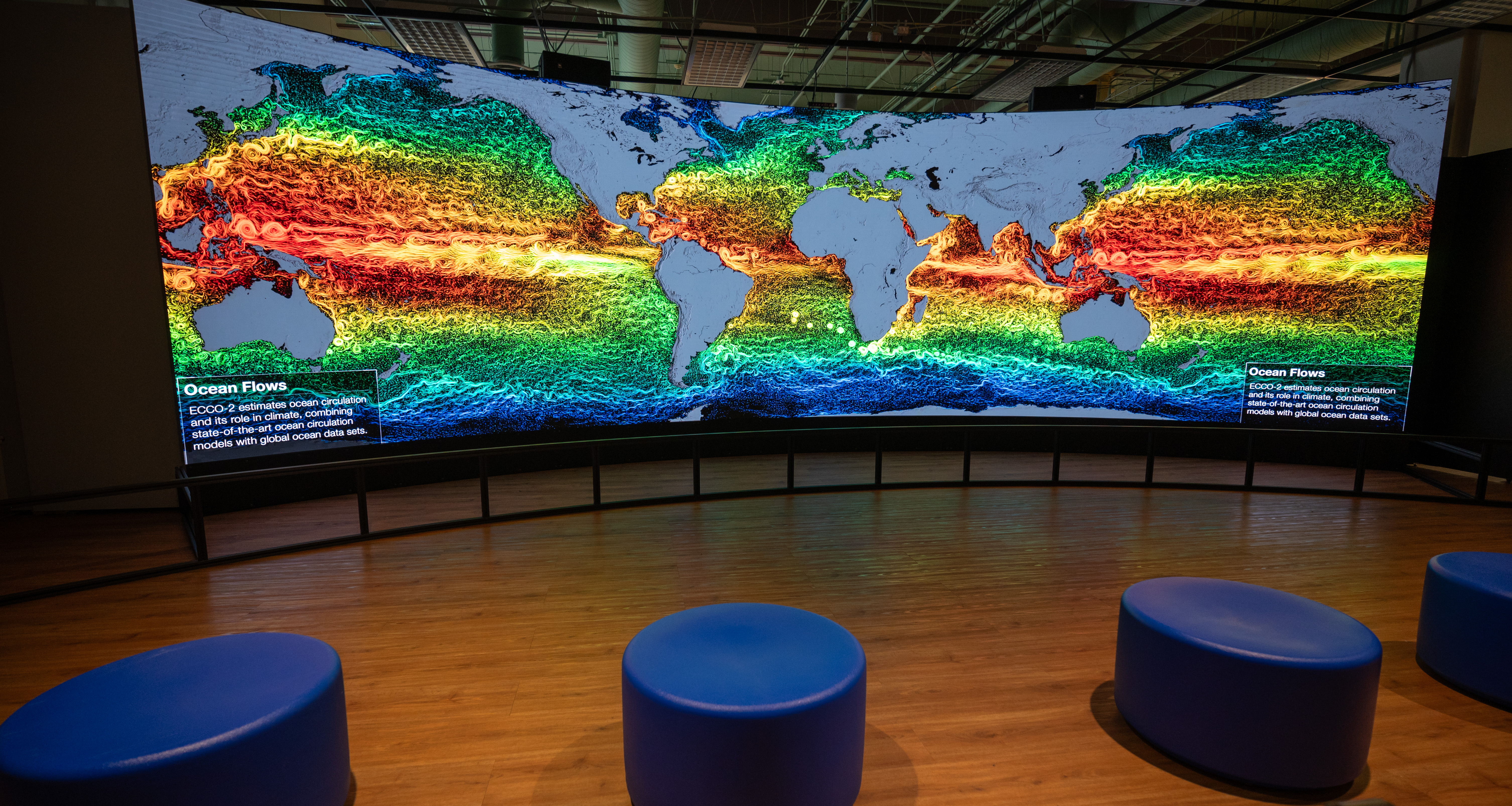 The Hyperwall with empty chairs, showing a data layer over a map of the world's oceans.