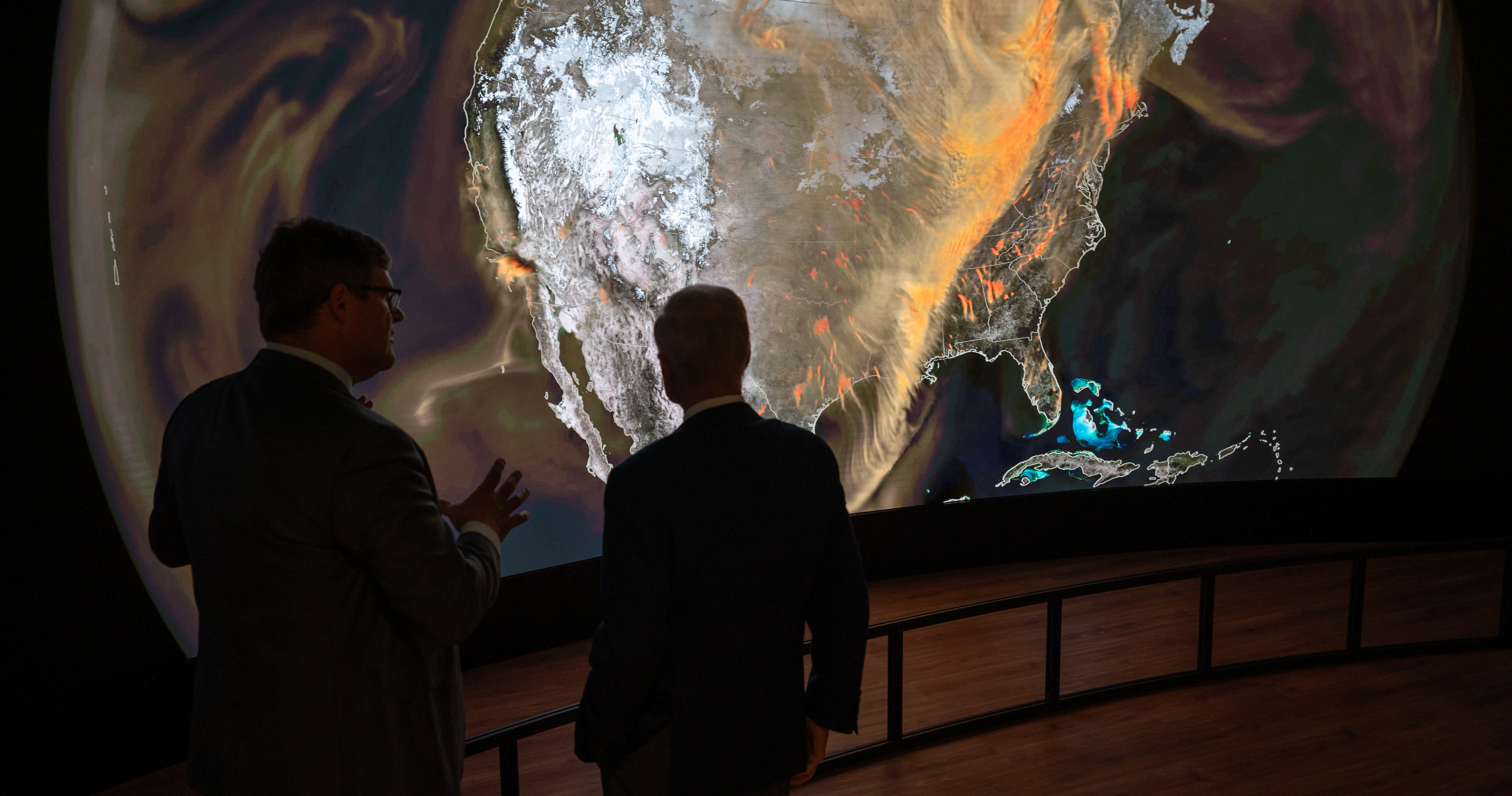Visitors to The Earth Information Center's display at the Smithsonion National Museum of Natural History viewing a large panel map of North America from space.